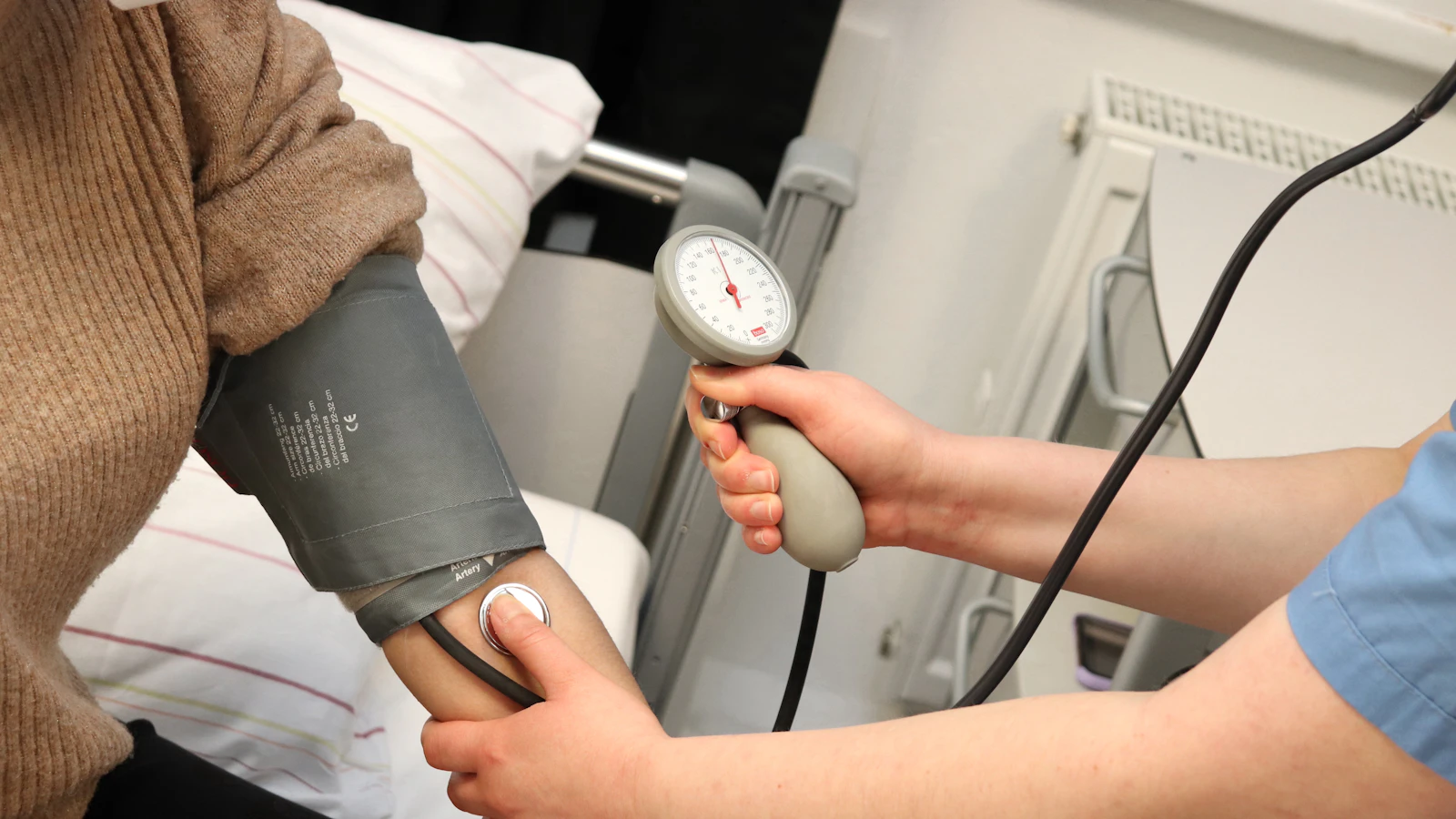 Een persoon houdt een bloeddrukmeter in de hand.