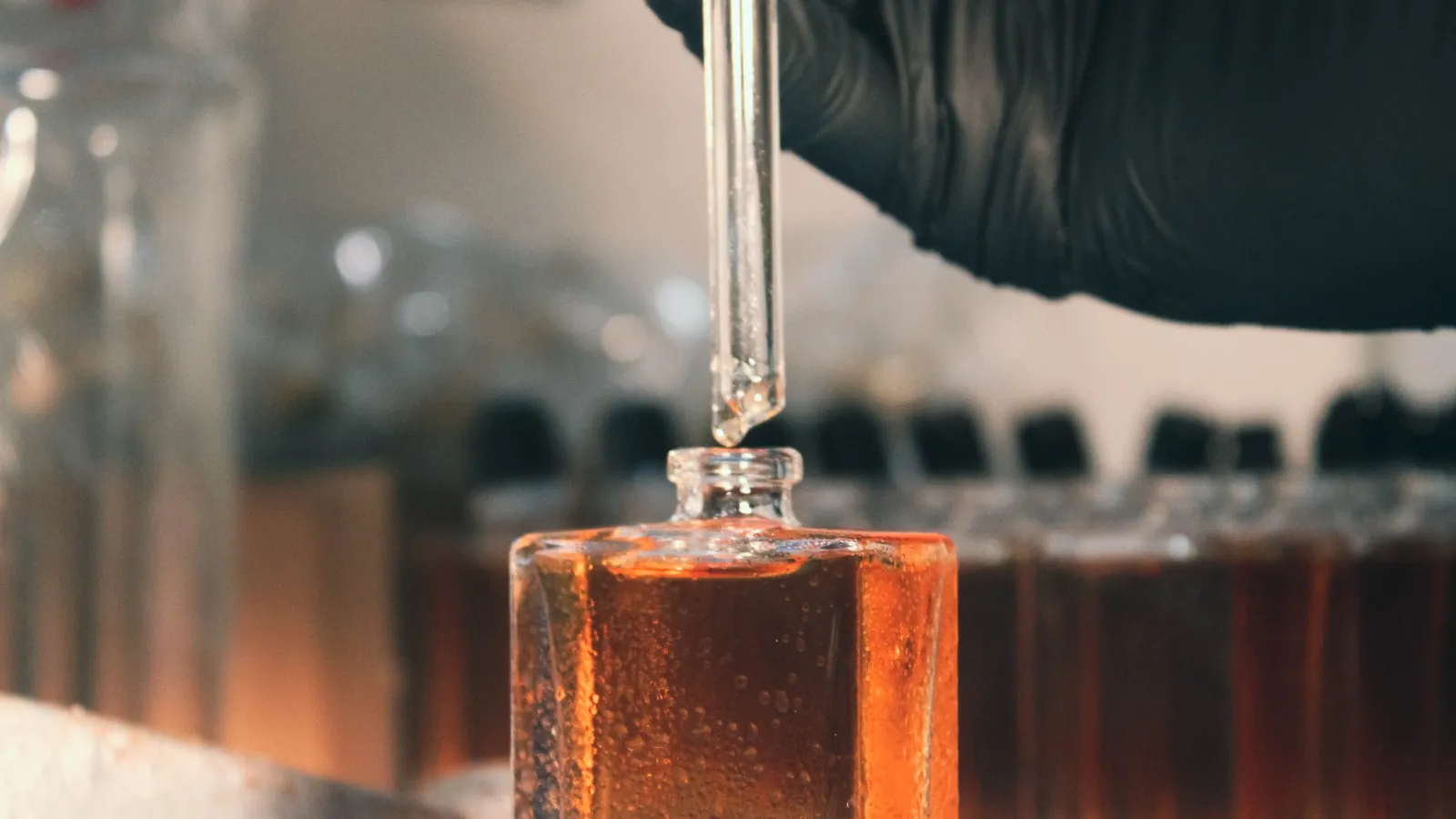 Een pipet doseert vloeistof in een glazen flesje op een laboratoriumtafel.