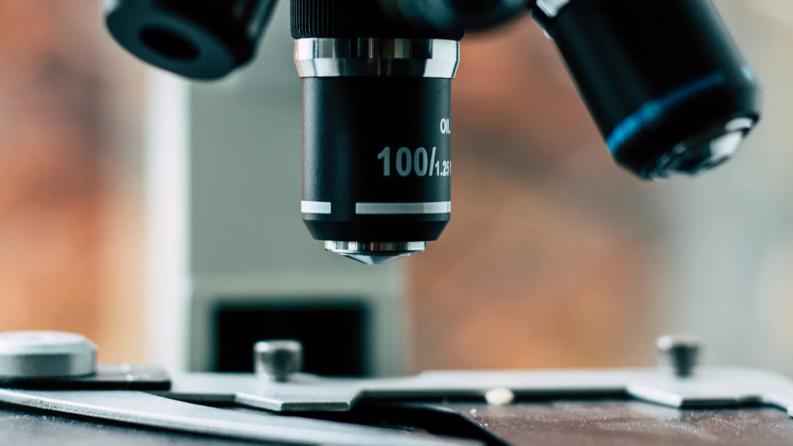 Close-up van de lens van een microscoop boven een objectglaasje.
