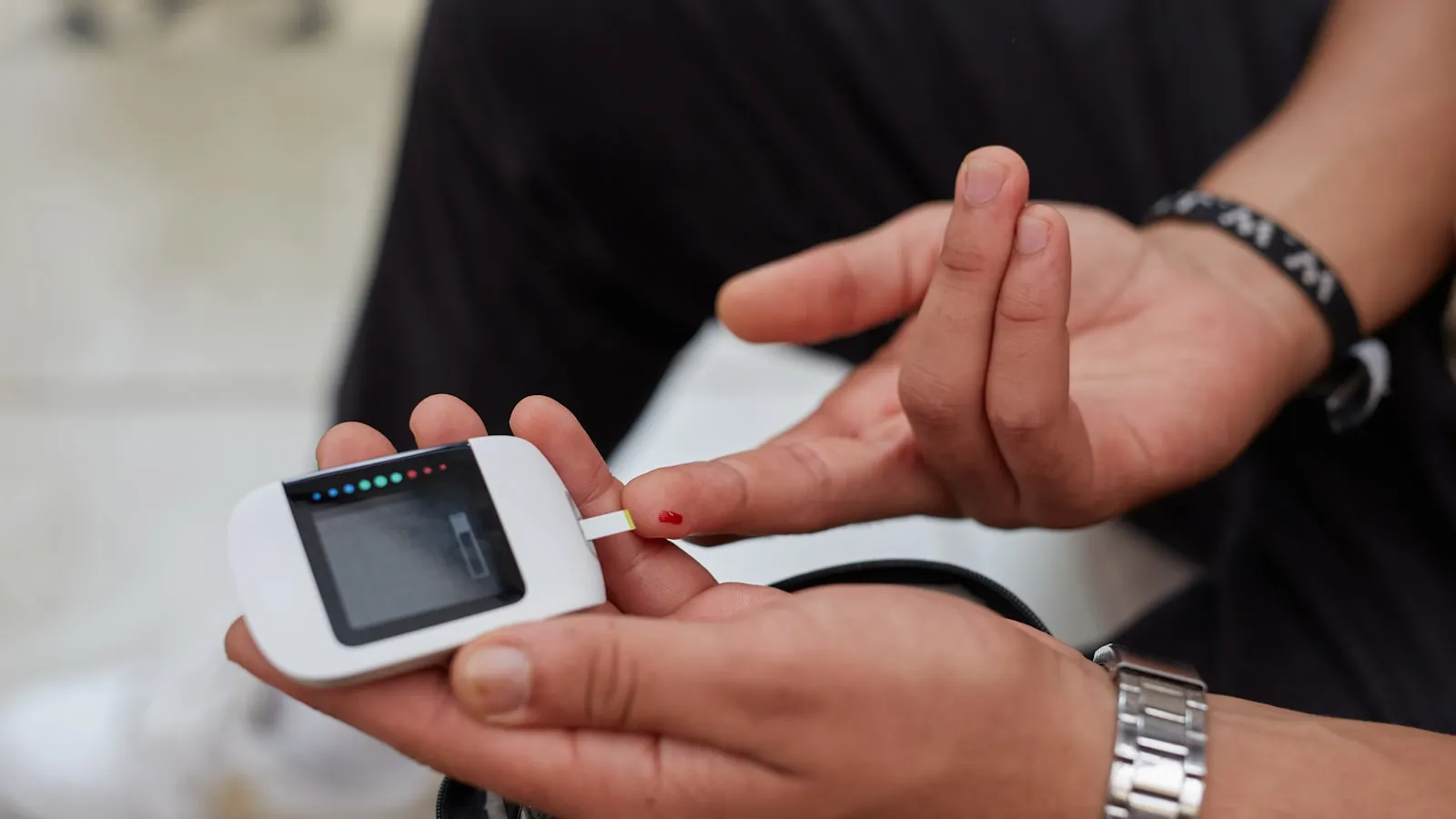 Iemand meet de bloedsuiker met een glucosemeter en een teststrip.