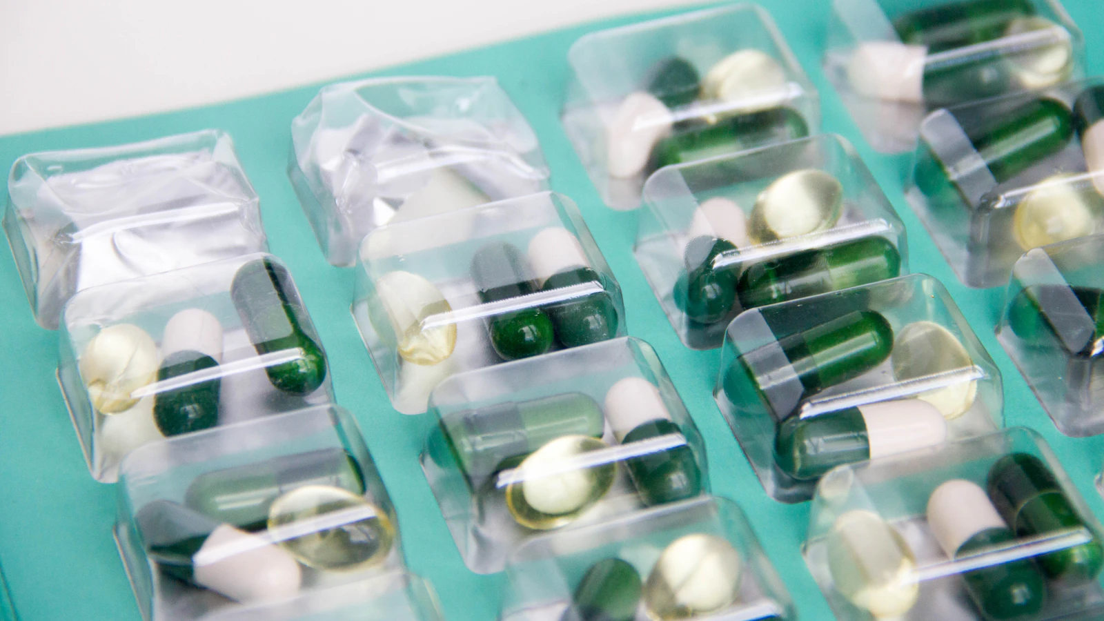 Een doordrukstrip met capsules en tabletten op een lichtblauw vlak.