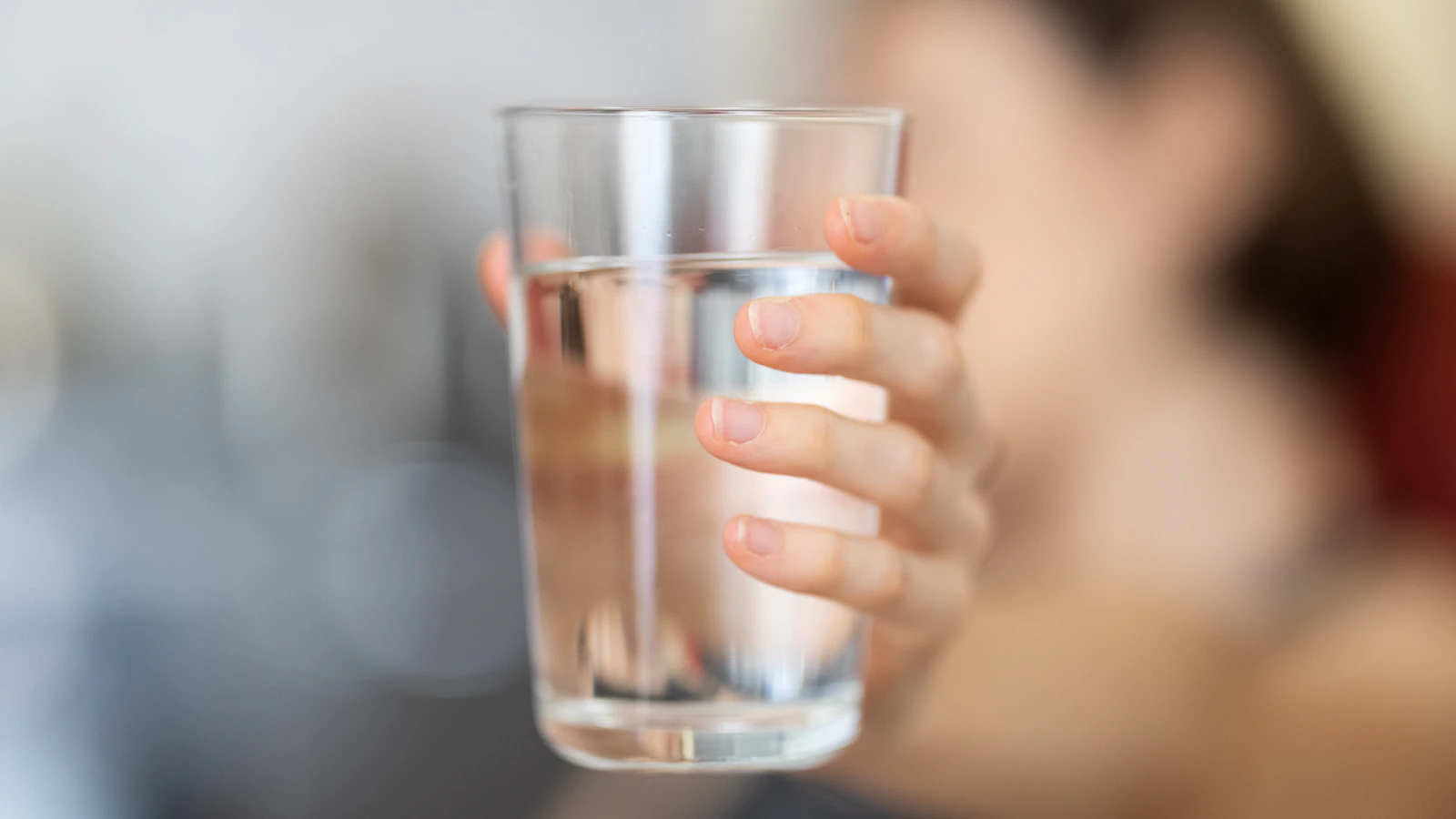 Iemand houdt een helder glas water vast.