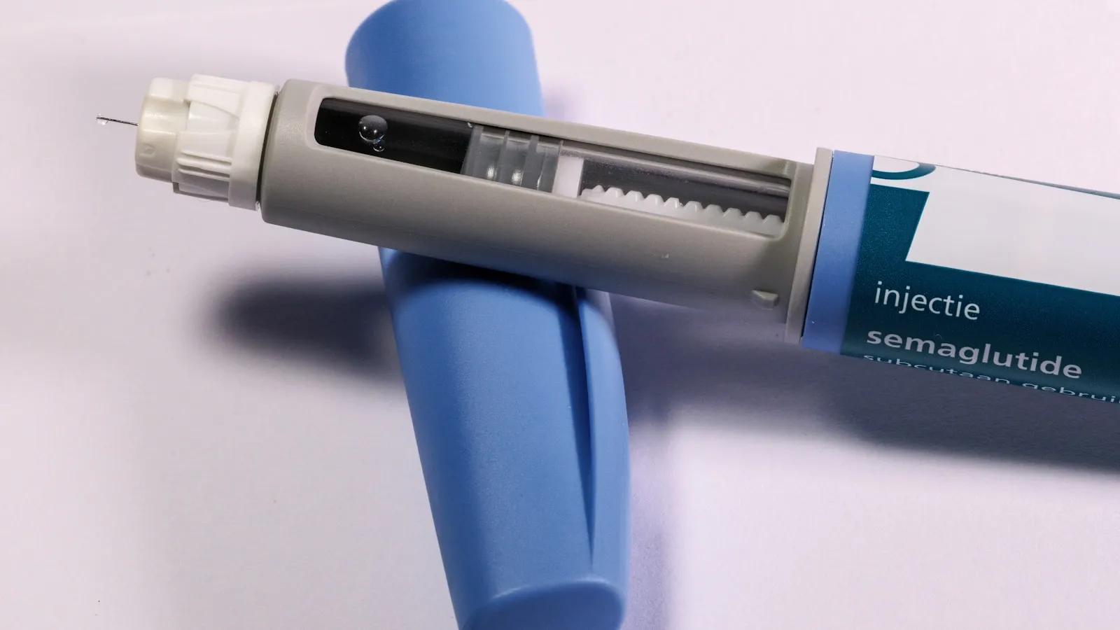 Een injectiepen met semaglutide ligt op een egaal gekleurde ondergrond.