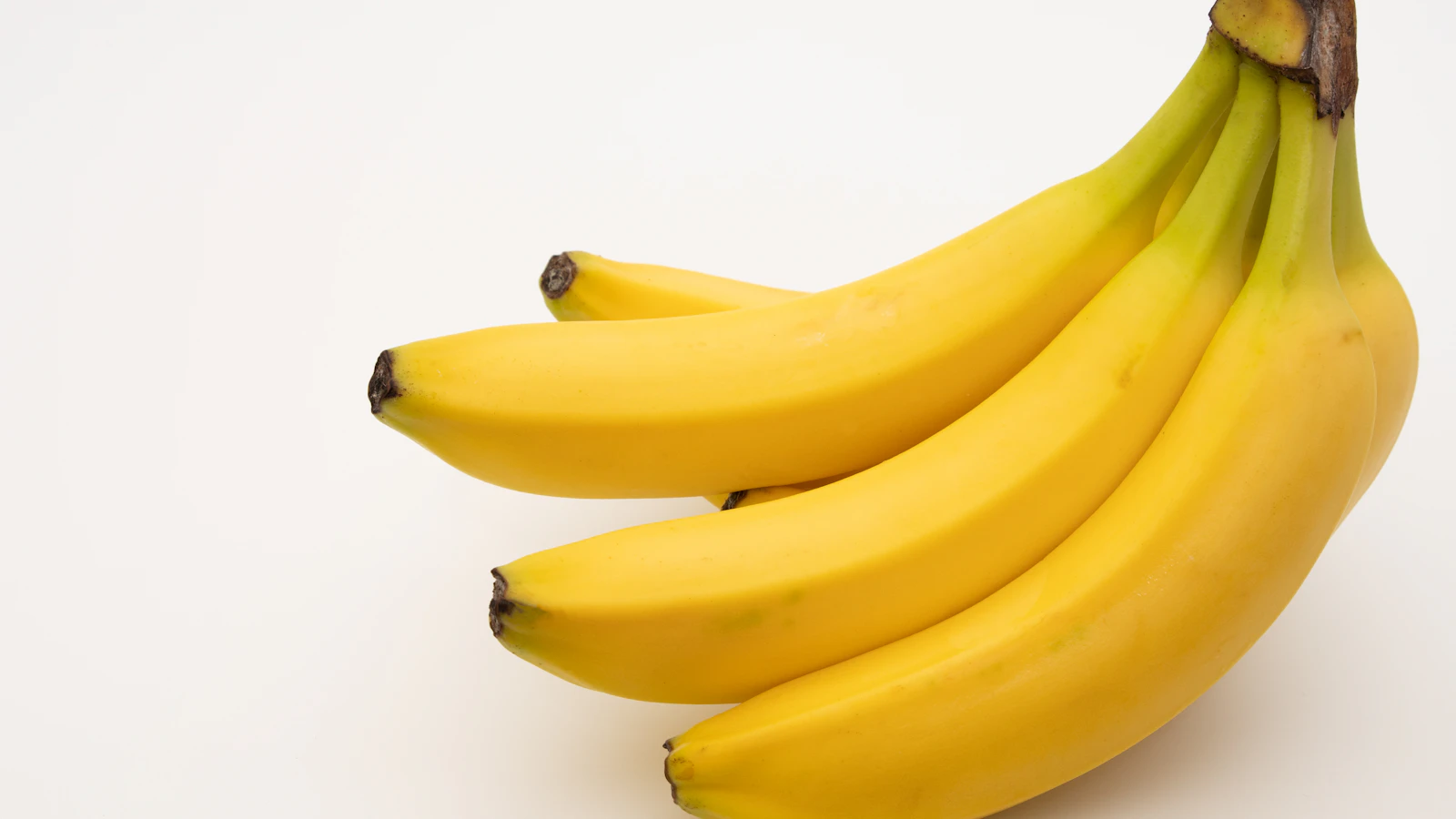 Een tros verse bananen op een lichte tafel, een bekende bron van kalium.