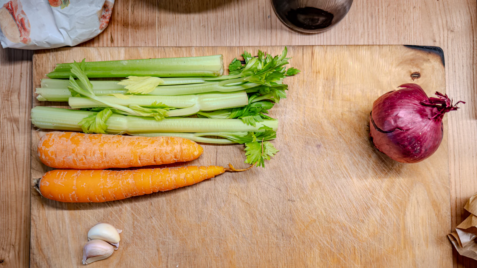 Fresh vegetables on a wooden chopping board in a kitchen.