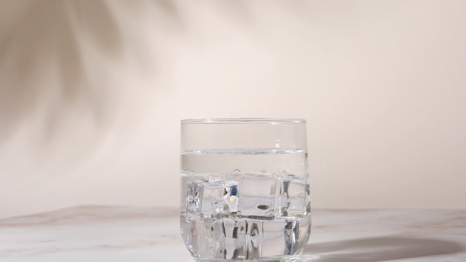 Een glas water staat op een marmeren aanrecht in de ochtend.
