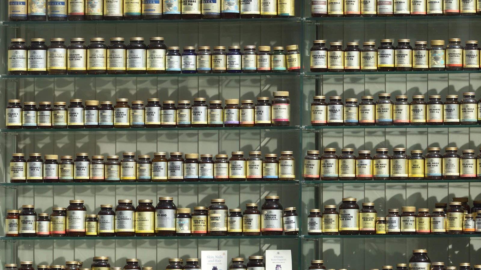 Planken vol geneesmiddelen met etiketten in een apotheek.