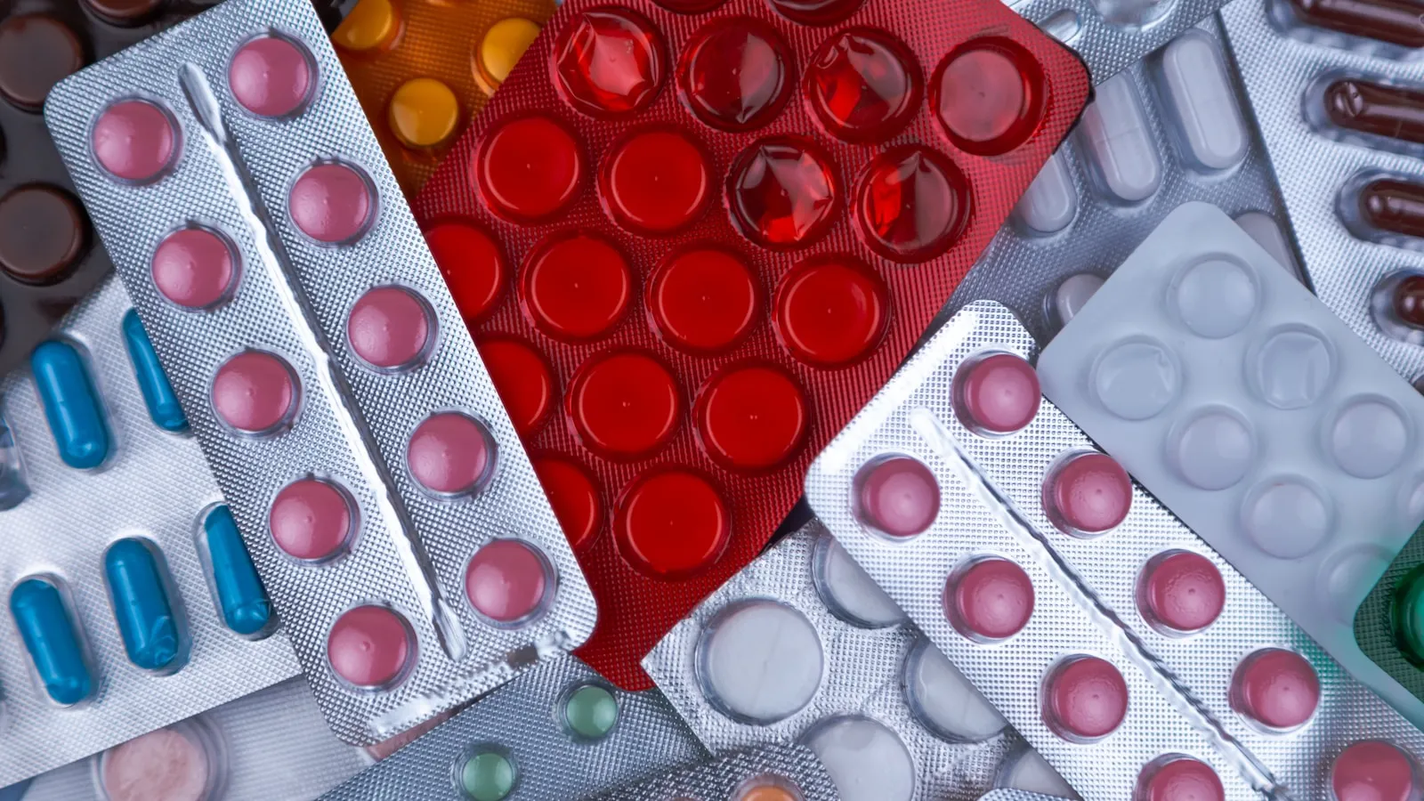 Een stapel doordrukstrips met tabletten en capsules in verschillende kleuren.